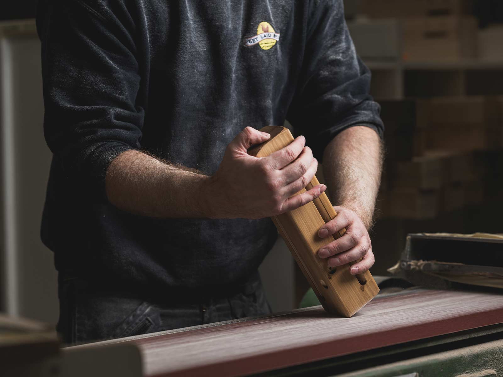 Craftsman sanding a wooden bed leg by hand in a workshop